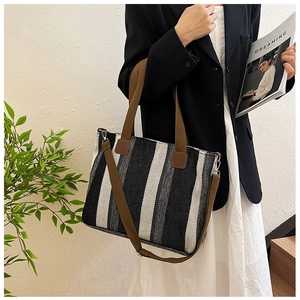 Detail of striped canvas tote bag with brown straps styled with a black blazer