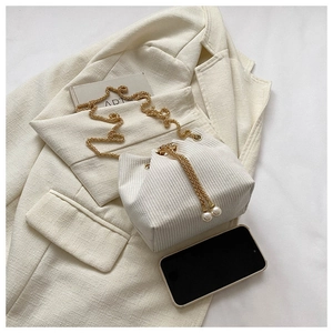 Detail einer beigen Cord-Beuteltasche mit Perlen-Kordelzug und goldenem Kettenriemen
