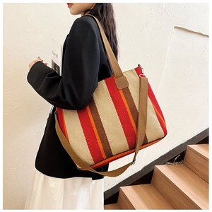 Detail view of large striped canvas tote bag showing dark brown faux leather handles