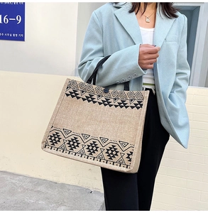 Detail of large linen tote bag showing geometric patterns and black shoulder straps