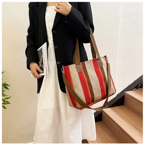 Detail of multi-color striped canvas tote bag with brown handles and a wide shoulder strap