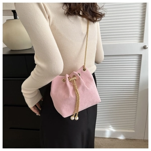 Detailansicht der rosa Cord-Beuteltasche mit Goldkette und dekorativen Perlenanhängern
