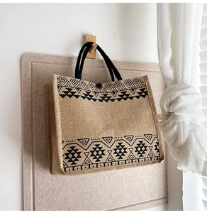 Detail view of linen tote bag featuring ethnic geometric patterns and black braided handles