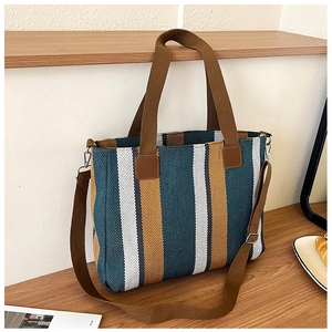 Close-up of colorful striped woven tote bag with brown leather straps on wood table