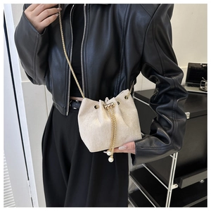 Detail der cremefarbenen Cord-Beuteltasche mit Perlenzugband und goldener Kette