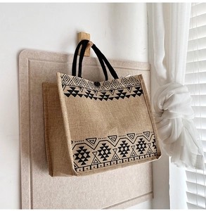 Close-up of linen tote bag featuring black geometric ethnic patterns and woven handles