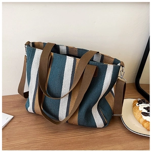 Detail view of canvas tote bag with blue, yellow and white stripes on wood desk