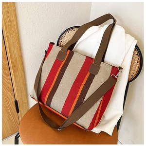 Detail of colorful striped canvas tote bag showing woven texture and brown adjustable strap