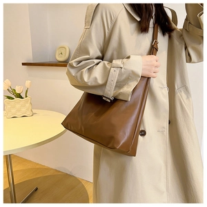 Detail view of smooth brown leather tote bag with adjustable shoulder strap on a model