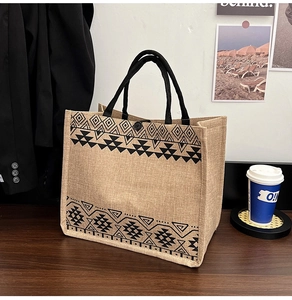 Detail of linen tote bag featuring geometric tribal pattern and black woven handles