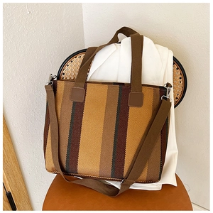 Detail of multi-color striped woven tote bag with brown fabric straps on chair