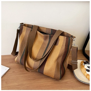 Detail of earthy striped woven tote bag with detachable wide strap on wooden desk