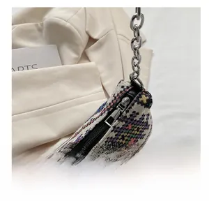 Detalle de la cremallera de plata y cadena metálica en el bolso de hombro de tejido