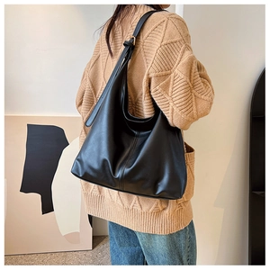 Detailed back view of a black leather hobo tote bag with vertical stitching and wide strap