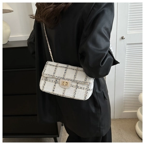 Detail van een witte tweed crossbody tas met blauw ruitpatroon en gouden sluiting