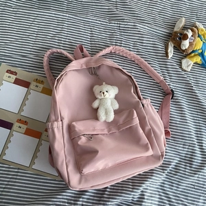 Pink nylon backpack featuring a cute white teddy bear charm and functional zip pockets