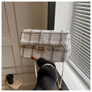 Detailopname van tweed crossbodytas met gouden ketting en metalen draaisluiting