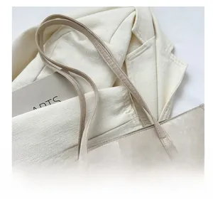 Detailed view of the stitched handle and oil-wax leather texture on a beige tote bag