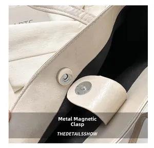 Close-up of magnetic metal clasp on creamy white leather bag with lychee texture