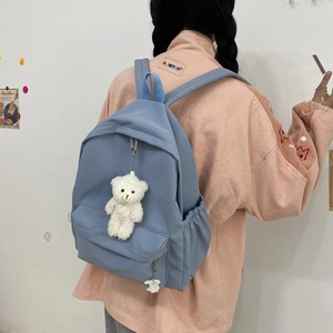 Detailed back view of a light blue nylon backpack with cute bear and bunny pendants