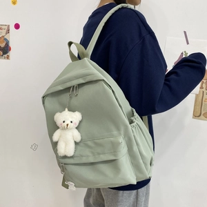 Detail view of mint green canvas backpack with side pockets and cute plush bear accessory