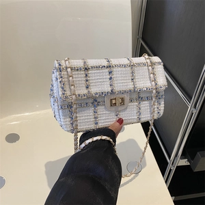 Blauw-witte tweed crossbodytas met gouden kettingriem en een metalen draaisluiting