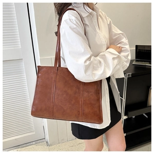 Side view of large brown vintage leather tote bag shown on model for daily commuting