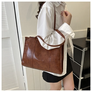 Detail of vintage brown oil-wax leather tote bag showing texture and shoulder strap