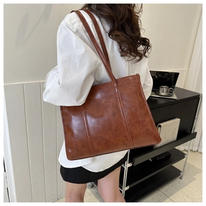 Brown oil wax leather tote bag shown on model highlighting the vintage shoulder strap style