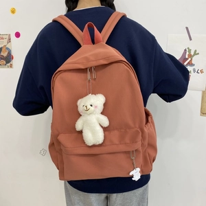 Macro detail of red nylon backpack with cute plush bear and rabbit pendants