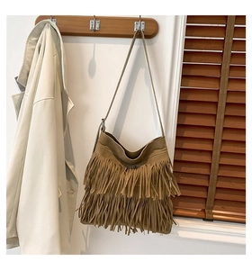 Detail einer Boho-Fransentasche aus braunem Wildleder an einem Holzhaken