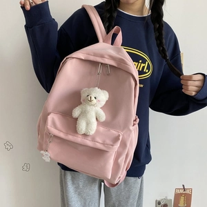 Pink nylon school backpack detail with cute plush bear pendant and front pocket view