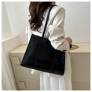 Detail view of large black oil-wax leather tote bag with vertical stitching on shoulder