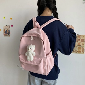 Rear view of a minimalist pale pink nylon backpack with a cute white plush bear pendant