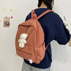 Detailed back view of a retro brick red nylon backpack with cute bear plush charms