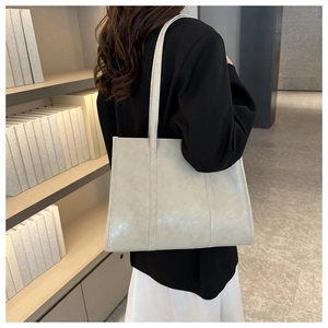 Minimalist cream white leather tote bag shown in a professional lifestyle setting