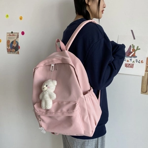 Pink minimalist nylon backpack for students shown from a side view with a bear charm