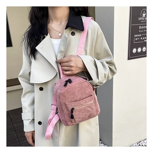 Pink corduroy mini backpack detail showing vertical texture and zipper on a model