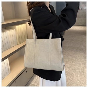 Minimalist beige tote bag in oil wax leather texture shown in a modern interior setting