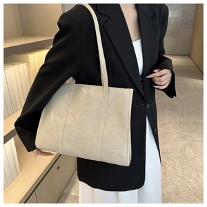 Detailed view of cream leather tote bag textured surface with parallel stitching accents