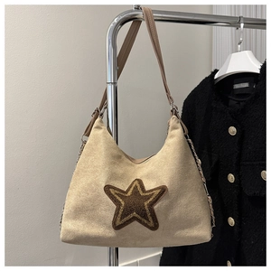 Detail van beige suède draagtas met grote bruine pluche ster en schouderketting