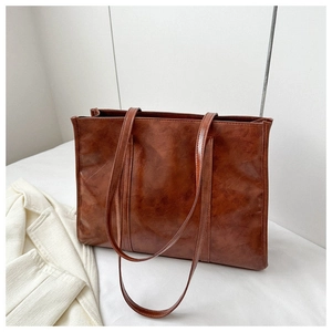 Detail of vintage brown oil-wax leather tote bag texture and large shoulder straps