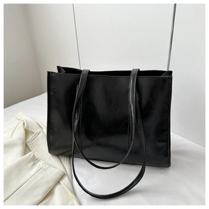 Detailed side view of glossy black faux leather tote bag with sturdy shoulder straps