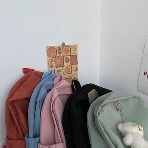 Minimalist nylon backpacks in multiple colors with bear pendant and side pocket detail