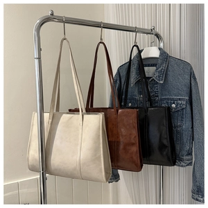 Detail view of large tote bags in cream white, caramel brown and black faux leather