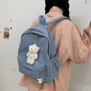 Detail view of light blue nylon backpack with cute bear and rabbit plush pendants