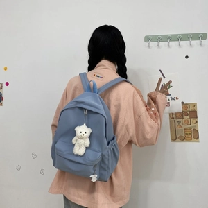 Detail view of sky blue nylon backpack with cute bear pendant and large front zipper pocket