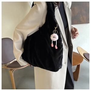 Close-up of black plush shoulder bag with a cute pink monster fuzzy charm accessory