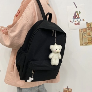 Detail view of the black canvas backpack featuring a plush bear and cloud charm on the side