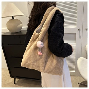 Detail of plush shoulder bag in camel faux fur with a cute pink monster charm accessory